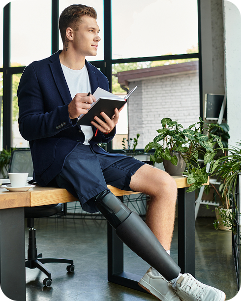 Hombre con prótesis de pierna sentado leyendo un libro en un ambiente de trabajo moderno